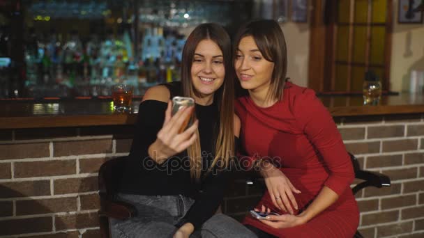 Dos hermosas mujeres tomar una selfie en el bar — Vídeos de Stock