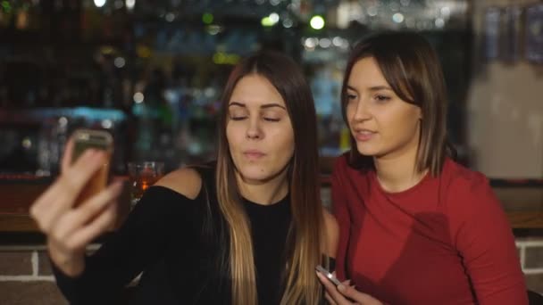 Dos hermosas mujeres tomar una selfie en el bar — Vídeos de Stock