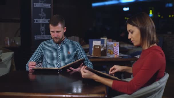 Όμορφο ζευγάρι στο δείπνο στο εστιατόριο κοιτάζοντας το μενού — Αρχείο Βίντεο