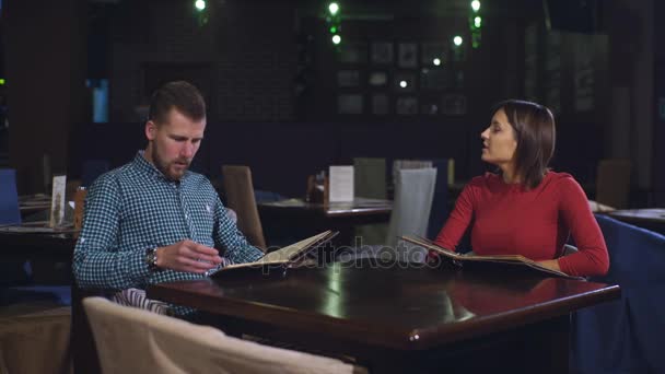 Pareja alegre con menú en un restaurante — Vídeo de stock