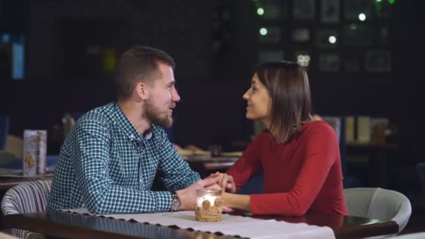 Pareja joven sentada en una mesa en un café y hablando — Vídeo de stock