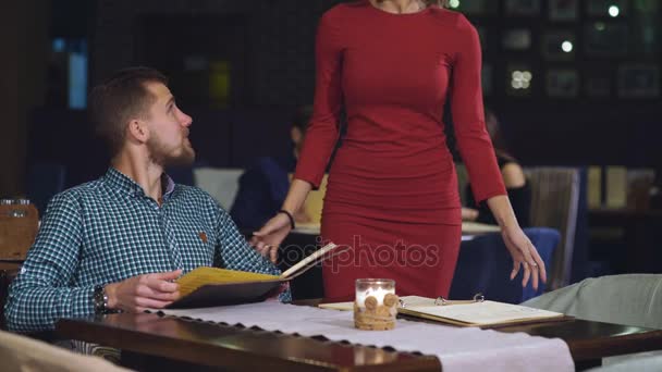 Красива пара за вечерею в ресторані шукає меню — стокове відео