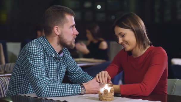 Pareja joven sentada en una mesa en un café y hablando — Vídeos de Stock