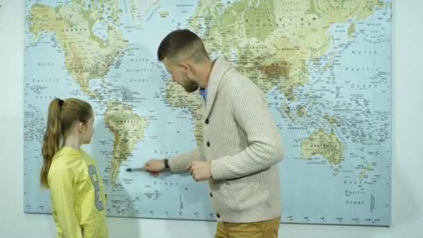 Schoolgirl showing countries on a map of the teacher — Stock Video