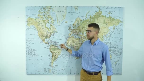 Молодой бизнесмен в очках показывает страну на карте мира — стоковое видео