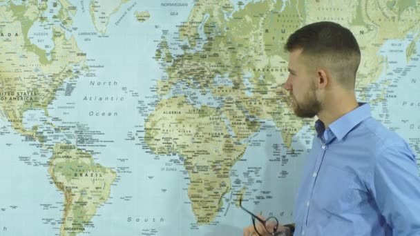 Молодой бизнесмен снимает очки и рассматривает географическую карту — стоковое видео