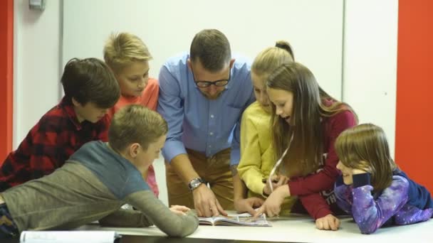 Un grupo de escolares examina la tarea para la lección — Vídeos de Stock