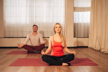 ince kadın ve adam poz Lotus Spor salonunda meditasyon arka plan üzerinde