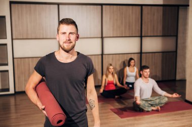 Yoga mat basılı tutup elini başının arkasında gülümseyen bir adam portresi