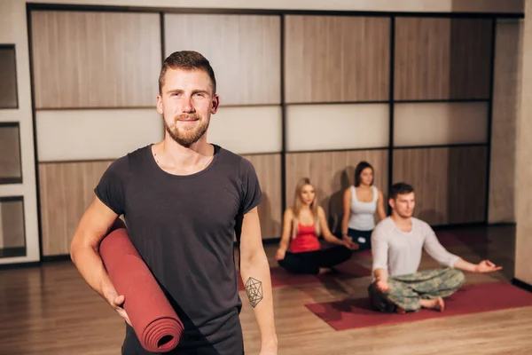 Yoga mat basılı tutup elini başının arkasında gülümseyen bir adam portresi