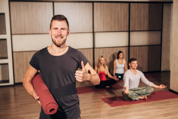 Portret van een man die houdt van yoga mat en duimen opdagen — Stockfoto