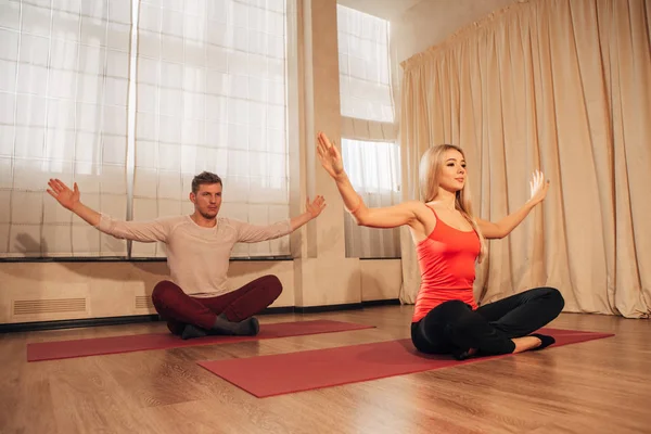 Hombre y mujer jóvenes haciendo ejercicios de yoga — Foto de Stock