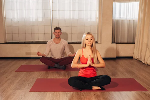 Hombre y mujer jóvenes haciendo ejercicios de yoga — Foto de Stock