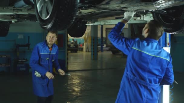 Mecánica de automóviles trabajando debajo de un coche levantado — Vídeo de stock