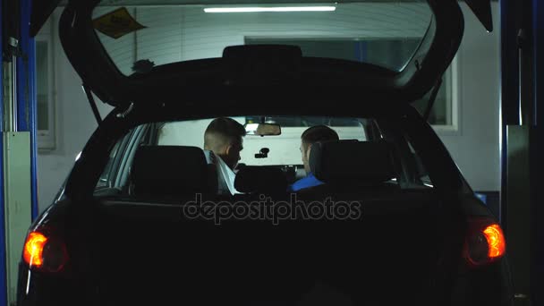 Zwei Automechaniker diagnostizieren Automechaniker, die im Auto sitzen — Stockvideo