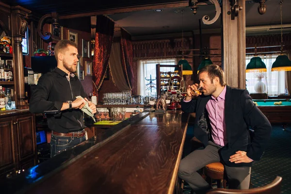Молодой человек разговаривает с барменом в баре — стоковое фото
