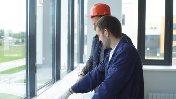 Joven capataz alegre está mostrando al arquitecto los problemas de la construcción — Vídeos de Stock