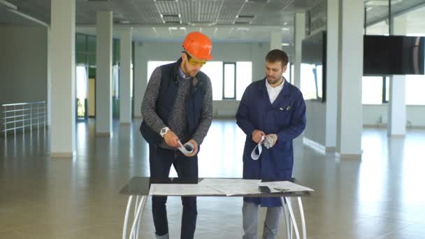Arkitekt eller ingeniør som arbeider med blåkopi og arkitektmodell i hall – stockvideo