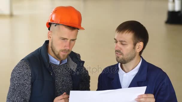 Ein Team von Bauarbeitern mit orangefarbenen Helmen am Arbeitsplatz in einer Fabrik — Stockvideo