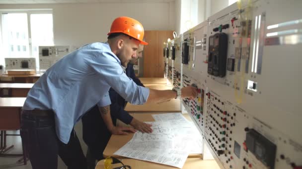 Jovem engenheiro tomando notas na sala de controle na fábrica — Vídeo de Stock