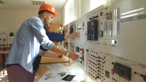 Joven ingeniero tomando notas en la sala de control en fábrica — Vídeo de stock