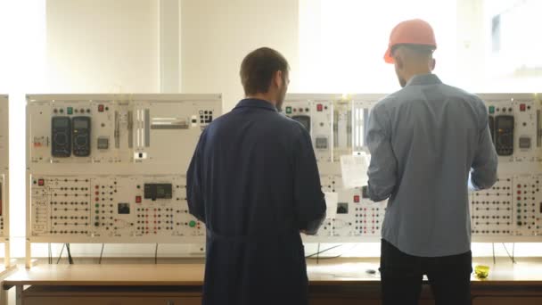 Jovem engenheiro tomando notas na sala de controle na fábrica — Vídeo de Stock