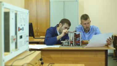 Laboratuvarda çalışan ve bir bilgisayarı kullanan genç mühendisler