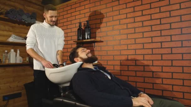 Парикмахер мыть волосы клиентам парикмахерской — стоковое видео