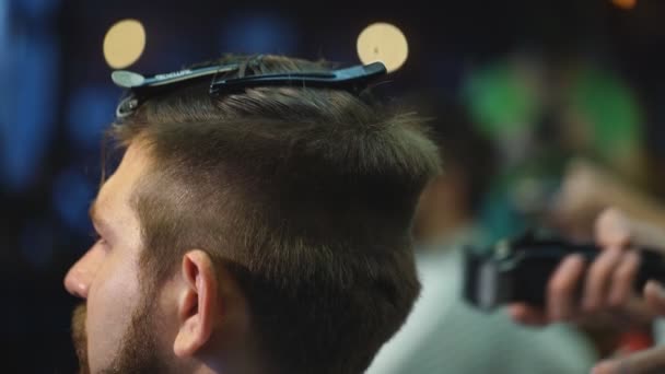 Het creëren van nieuwe haar look. Young bebaarde man krijgen kapsel door Kapper zittend in de stoel bij barbershop — Stockvideo