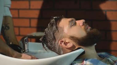 Berber dükkanında müşterilerin saçını yıkayan kuaför.