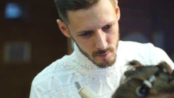 Jovem barbeiro bonito fazendo corte de cabelo de homem barbudo atraente na barbearia — Vídeo de Stock