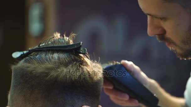 Maestro corta el pelo y la barba de los hombres en la peluquería, peluquería hace peinado para un hombre joven — Vídeos de Stock