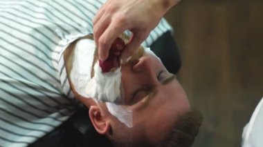 Berber dükkanında sakal tıraşı olan bir müşteri.