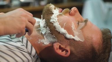 Berber dükkanında sakal tıraşı olan bir müşteri.