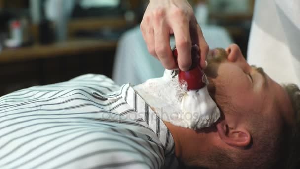 Клиент во время бритья бороды в парикмахерской — стоковое видео