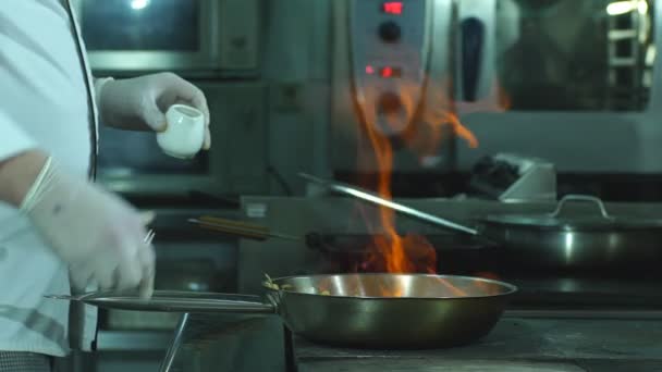 Ein Koch blättert Gemüse in einer Pfanne — Stockvideo