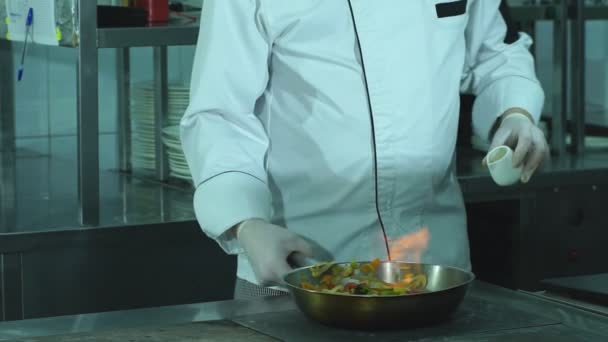 Um chef lançando legumes em uma frigideira — Vídeo de Stock