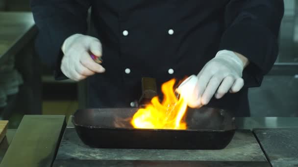 Bottle pours liquid onto pan. Meat and green vegetable. Fried beef and asparagus. Chef makes flambe steak. — Stock Video