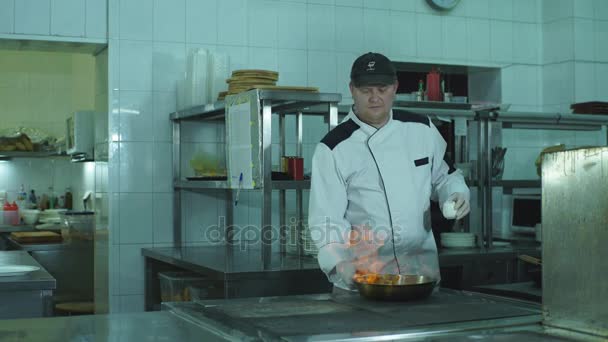 Um chef lançando legumes em uma frigideira — Vídeo de Stock