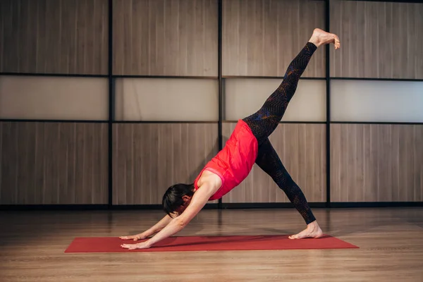 Mujer haciendo yoga en casa abajo perro pose dividida — Foto de Stock