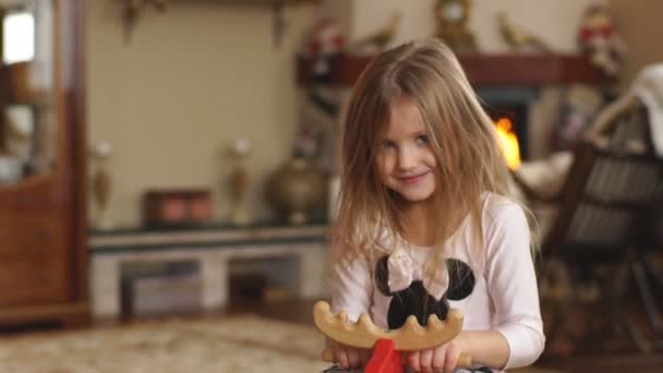 Дівчина на іграшковому коні вдома — стокове відео