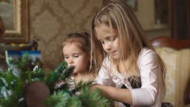 iki küçük kız bir Noel çelenk yapmak