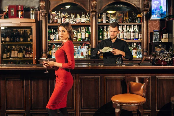 Красивая женщина в красном платье стоит рядом с баром коктейль — стоковое фото