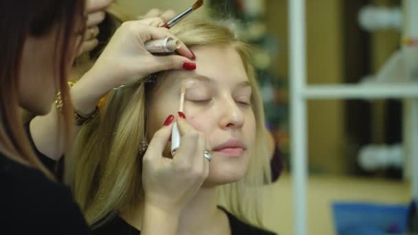 Joven hermosa mujer aplicando maquillaje por maquillador — Vídeos de Stock