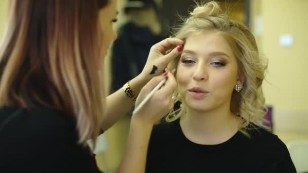 Jonge mooie vrouw aanbrengen van make-up door make-up kunstenaar — Stockvideo