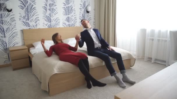 En glad ungt par faller på sängen — Stockvideo