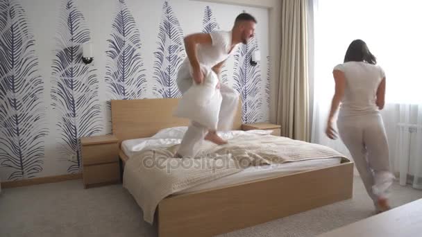Пара веселится с битвой подушками в постели — стоковое видео