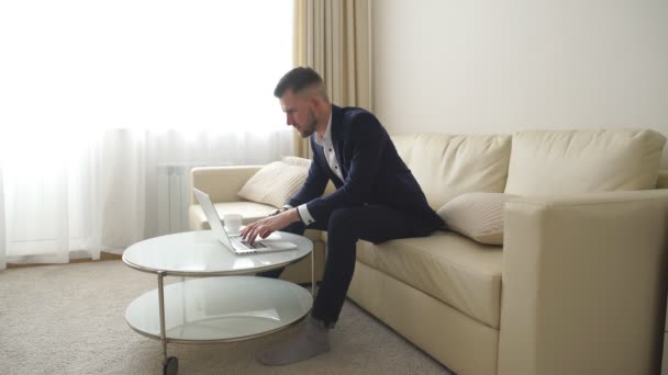 Mladý úspěšný pohledný muž, práce s počítačem v hotelovém pokoji — Stock video