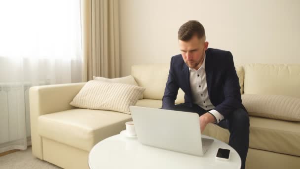 Joven hombre guapo exitoso que trabaja con la computadora en una habitación de hotel — Vídeo de stock