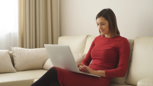 Hermosa mujer joven utiliza un ordenador portátil en una habitación de hotel — Vídeo de stock